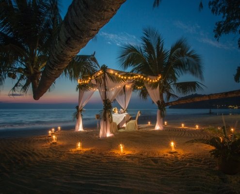 A romantic table set in a pergola on a beach