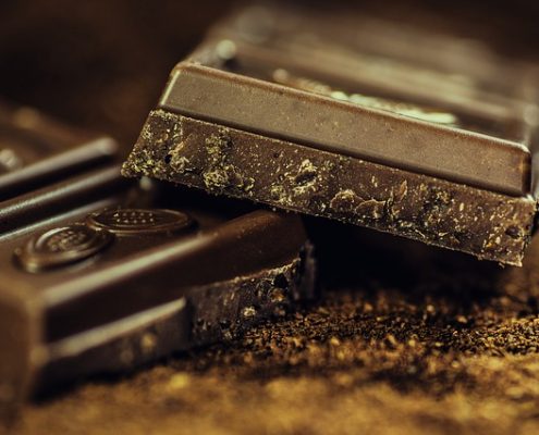 The Best Books On Chocolate 4 two pieces of chocolate stacked with chocolate shavings on a dark background