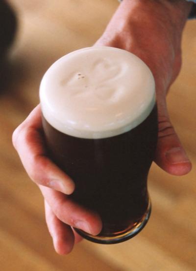 Hand holding half pint of Guinness Beer