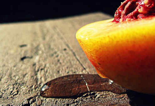 aphrodisiac peach sliced in half on a wooden background