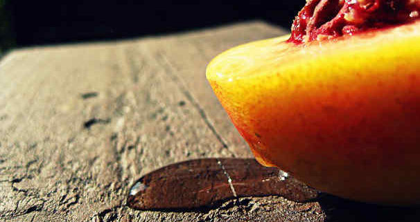 aphrodisiac peach sliced in half on a wooden background