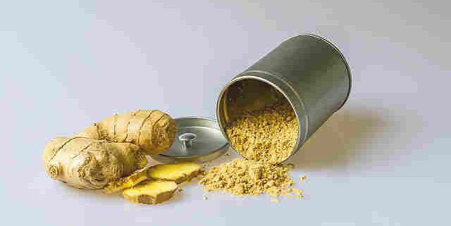 closeup of powdered and fresh ginger slices on a white background