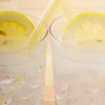 closeup of two side by side limoncello spritz cocktails in rocks glasses with ice and a lemon wheel garnish in each glass