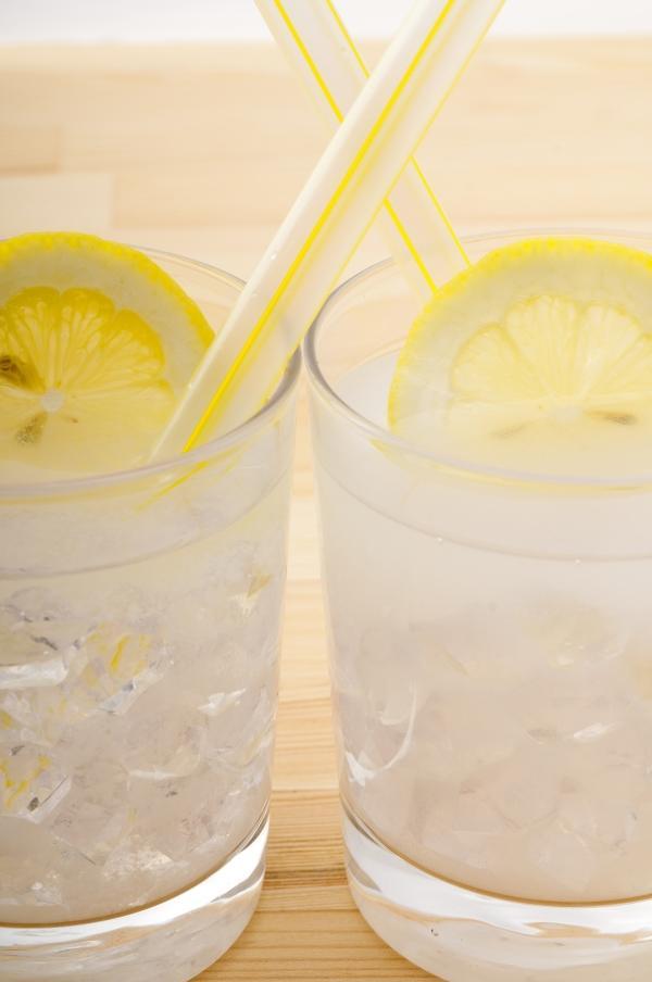 closeup of two side by side limoncello spritz cocktails in rocks glasses with ice and a lemon wheel garnish in each glass