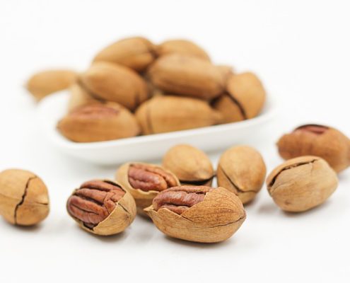 white bowl with nuts and several laying in front - a good source of manganese