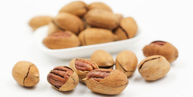 white bowl with nuts and several laying in front - a good source of manganese