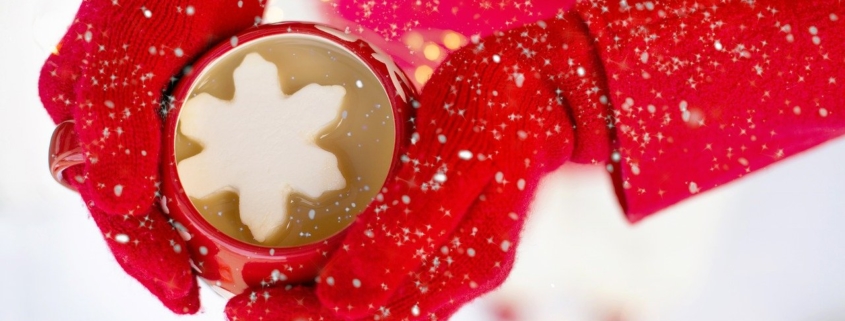 woman in red gloves holding a hot chocolate cocktail with a snowflake marshmallow