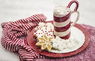 closeup of The Snuggler, a hot chocolate cocktail in a candy cane striped mug with a candy cane garnish and Christmas cookies on the side