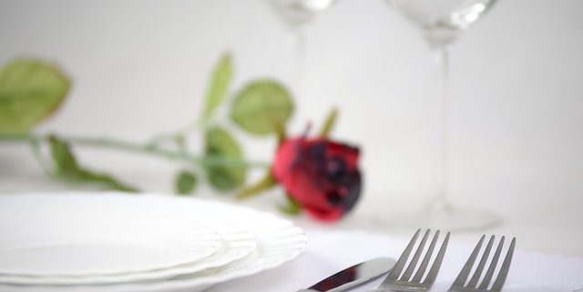 closeup of dinner table setting with a red rose to illustrate what we consider romantic