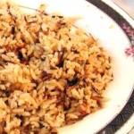 closeup of brown rice pilaf in a white bowl with black trim