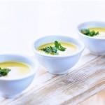 Three white bowls of peach gazpacho on a whitewashed wooden table