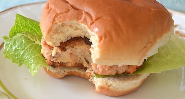 closeup of a mushroom and salmon cake with truffle mayonnaise served as a burger with romaine on a white plate