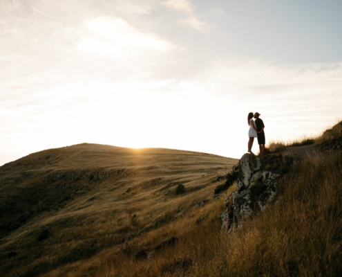 A couple embracing on top of a New Zealand hillside at sunset