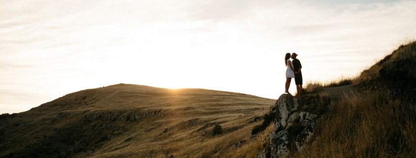 A couple embracing on top of a New Zealand hillside at sunset