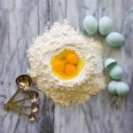 Blue heirloom eggs in flour with measuring spoons