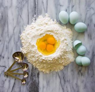 Blue heirloom eggs in flour with measuring spoons