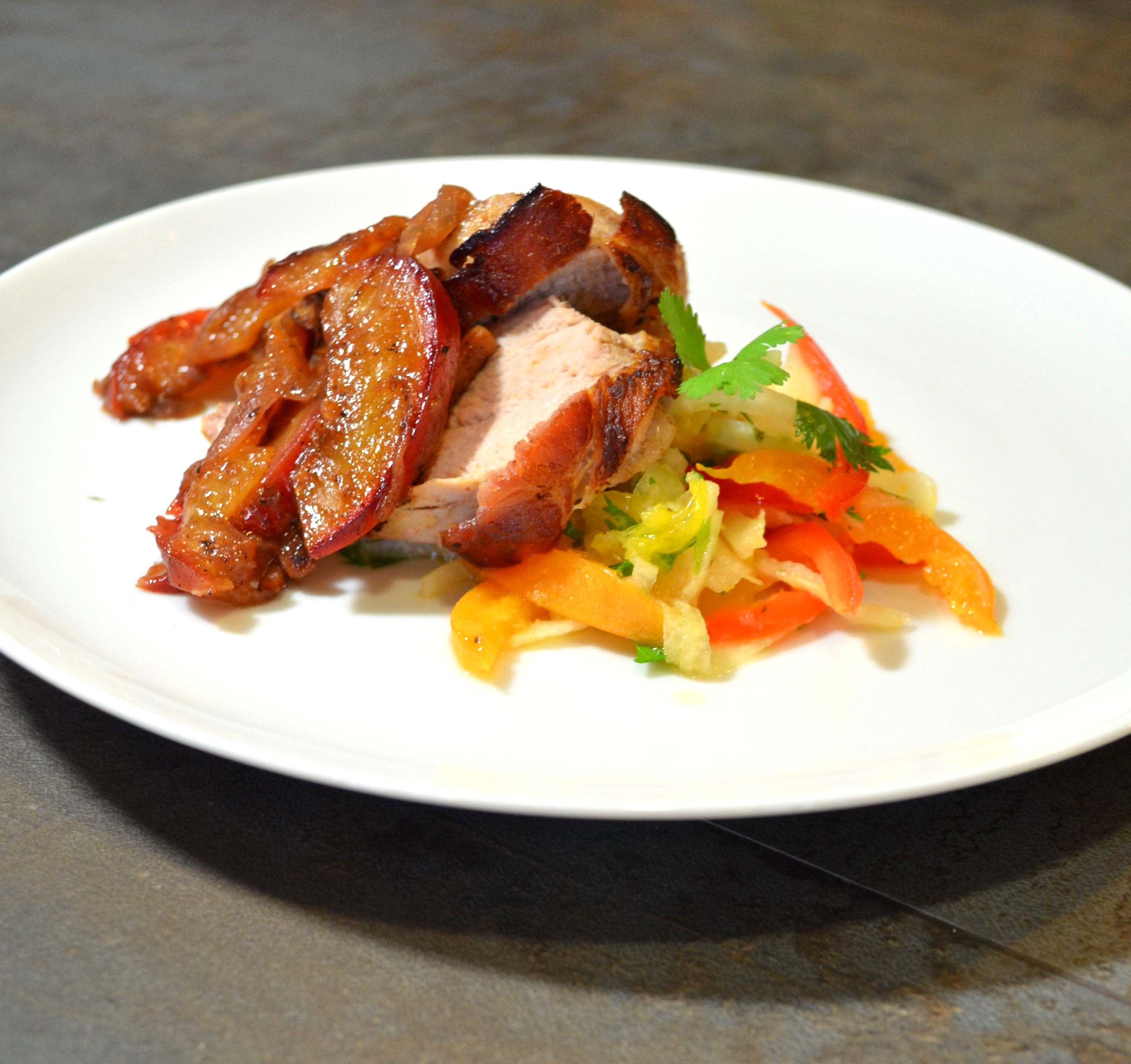 bacon-wrapped pork tenderloin with apricots on a white plate