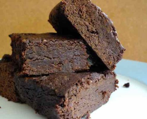 Recipe for Black Bean Chocolate Brownies 3 black bean chocolate brownies on a white plate with a dark yellow background