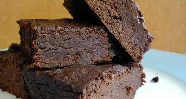 black bean chocolate brownies on a white plate with a dark yellow background