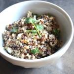 closeup of warm quinoa salad in a white bowl on a dark background