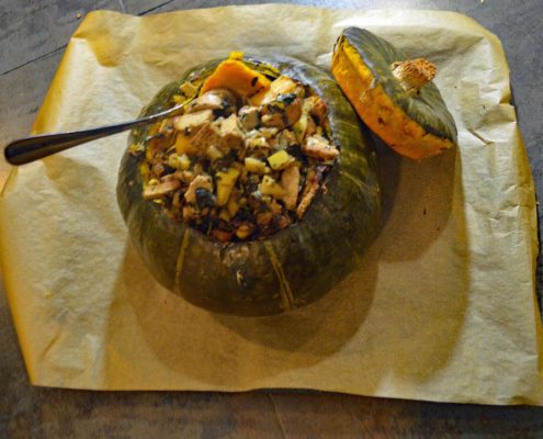 Vegetarian Roasted, Stuffed Kabocha Squash on top of parchment with a large, silver serving spoon
