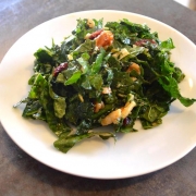 Closeup of Massaged Kale Salad with Cranberries and Persimmon on a small, white plate