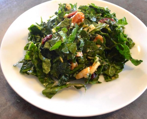 Closeup of Massaged Kale Salad with Cranberries and Persimmon on a small, white plate