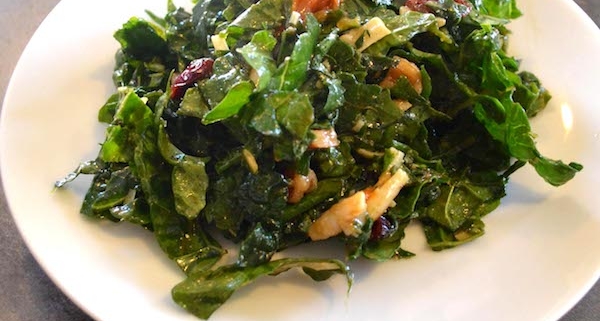 Closeup of Massaged Kale Salad with Cranberries and Persimmon on a small, white plate