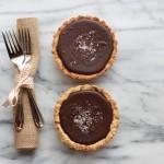 Closeup of Dark Chocolate Ganache Tart with Honey Dijon Pretzel Crust on a marble background with a fork and napkin