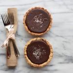 Recipe for Dark Chocolate Ganache Tart with a Pretzel Crust 3 Closeup of Dark Chocolate Ganache Tart with Honey Dijon Pretzel Crust on a marble background with a fork and napkin