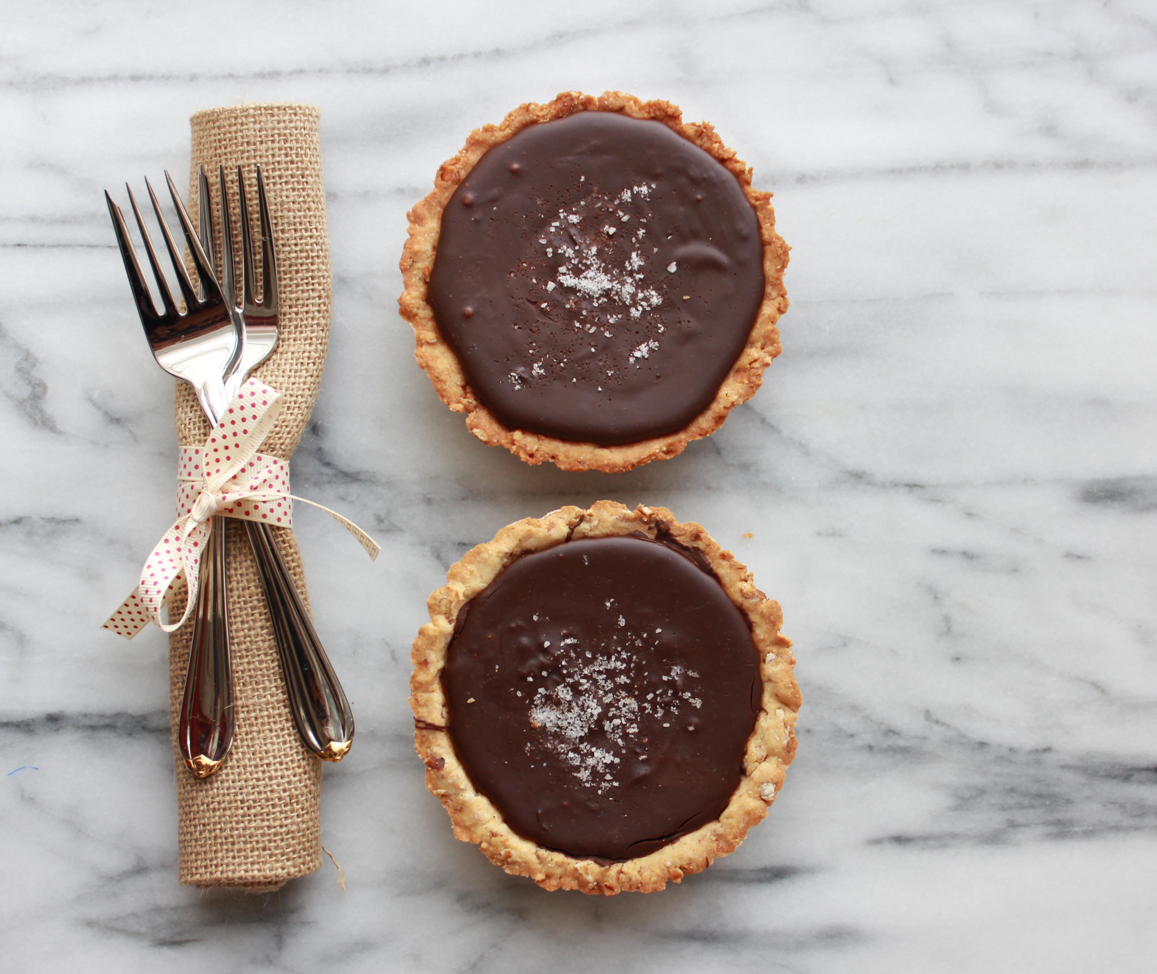 Closeup of Dark Chocolate Ganache Tart with Honey Dijon Pretzel Crust on a marble background with a fork and napkin