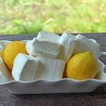 closeup of a pile of lemon marshmallows on a plate with two fresh lemons