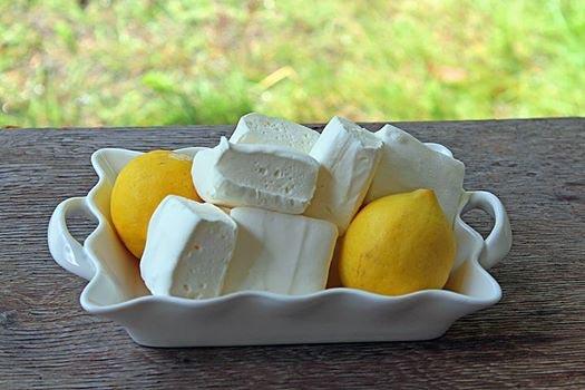 closeup of a pile of lemon marshmallows on a plate with two fresh lemons