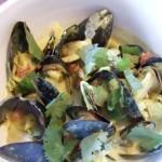 closeup of cockles, mussels and clams with cilantro and coconut