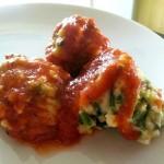 closeup of three ricotta gnudi with marinara on a white plate