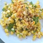 closeup of corn salad with finger lime and wild arugula on a white plate