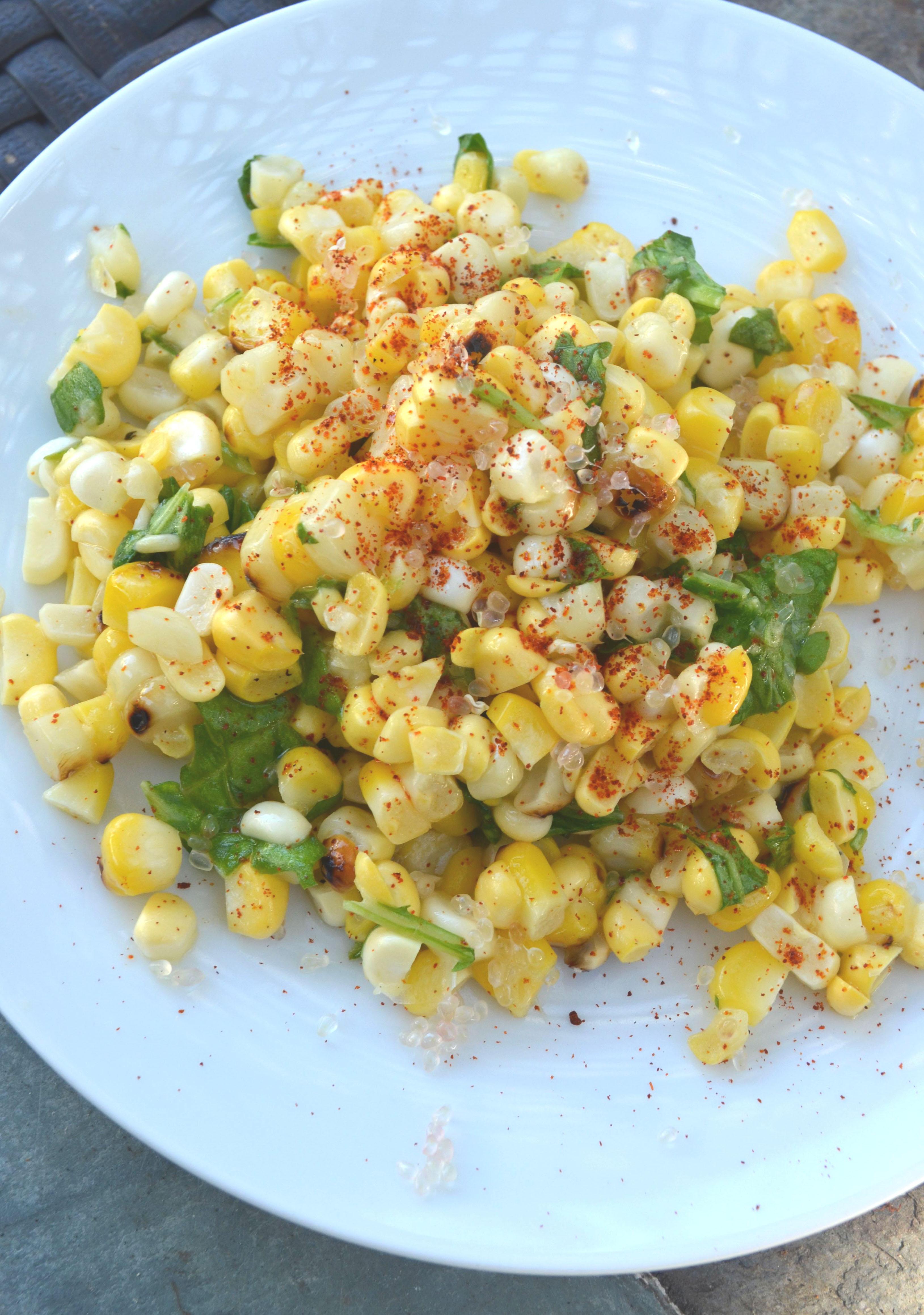 closeup of corn salad with finger lime and wild arugula on a white plate