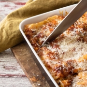 Easy Meatless Lasagna Recipe with Tofu 2 closeup of meatless lasagna in a baking dish with someone cutting it with a chef's knife
