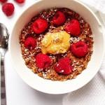 Cacao Raspberry Oats in a white bowl on a white background with a silver spoon to the left of the bowl