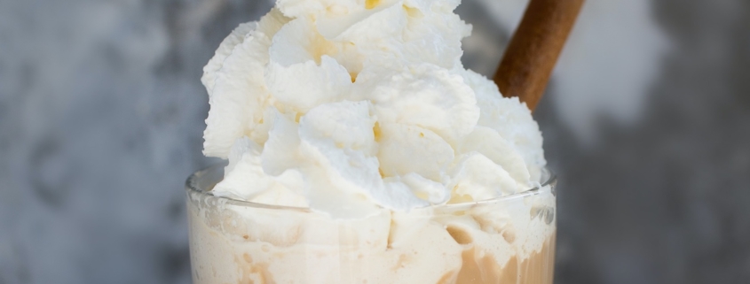 coffee cocktail topped with whipped cream and a cinnamon stick