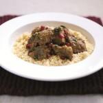 Lamb Tagine with Pomegranates over Couscous in a White Bowl