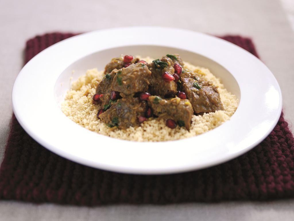 Lamb Tagine with Pomegranates over Couscous in a White Bowl