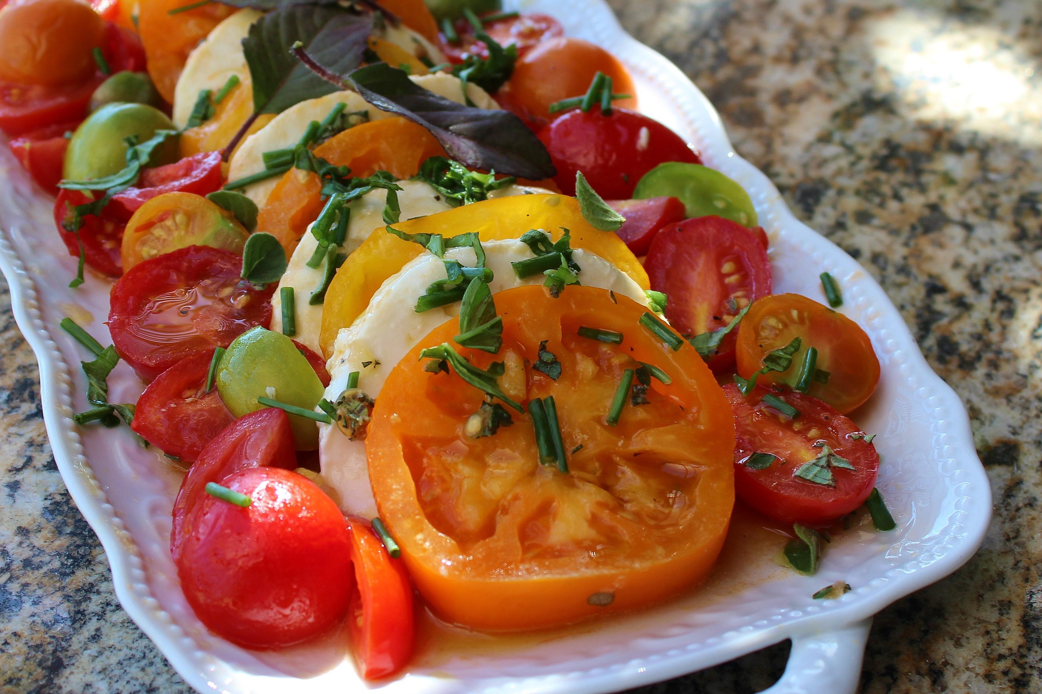 closeup of tomato mozzarella salad on a white serving platter