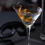 A Sexy Cocktail Recipe with Scottish Flair 2 closeup fo Smoke on the Water, the sexy vodka cocktail in a martini glass with an orange twist. A black mask is in the background