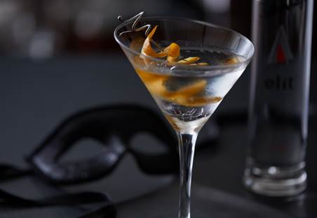 closeup fo Smoke on the Water, the sexy vodka cocktail in a martini glass with an orange twist. A black mask is in the background