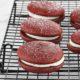 Red Velvet Sandwich Cookies on a black, metal rack above a white background