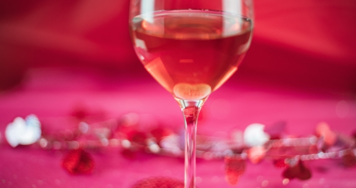 Pink wine on a pink background with valentine confetti