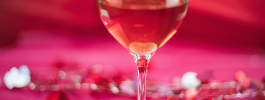 Pink wine on a pink background with valentine confetti to illustrate best valentine wine