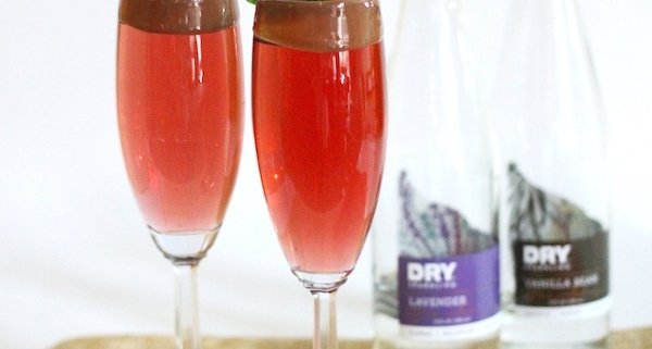 closeup of dry sparkling romantic cocktail in two flutes with two dry sparkling bottles in the background