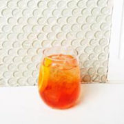 An Aperol Spritz in a rocks glass against a white background